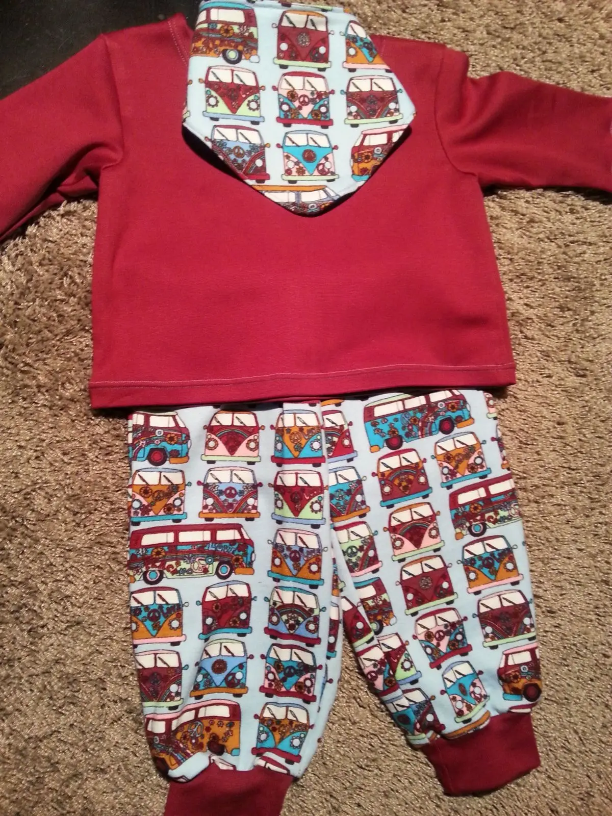 Roter Kinderpullover mit bunt gemusterter Hose und Tuch