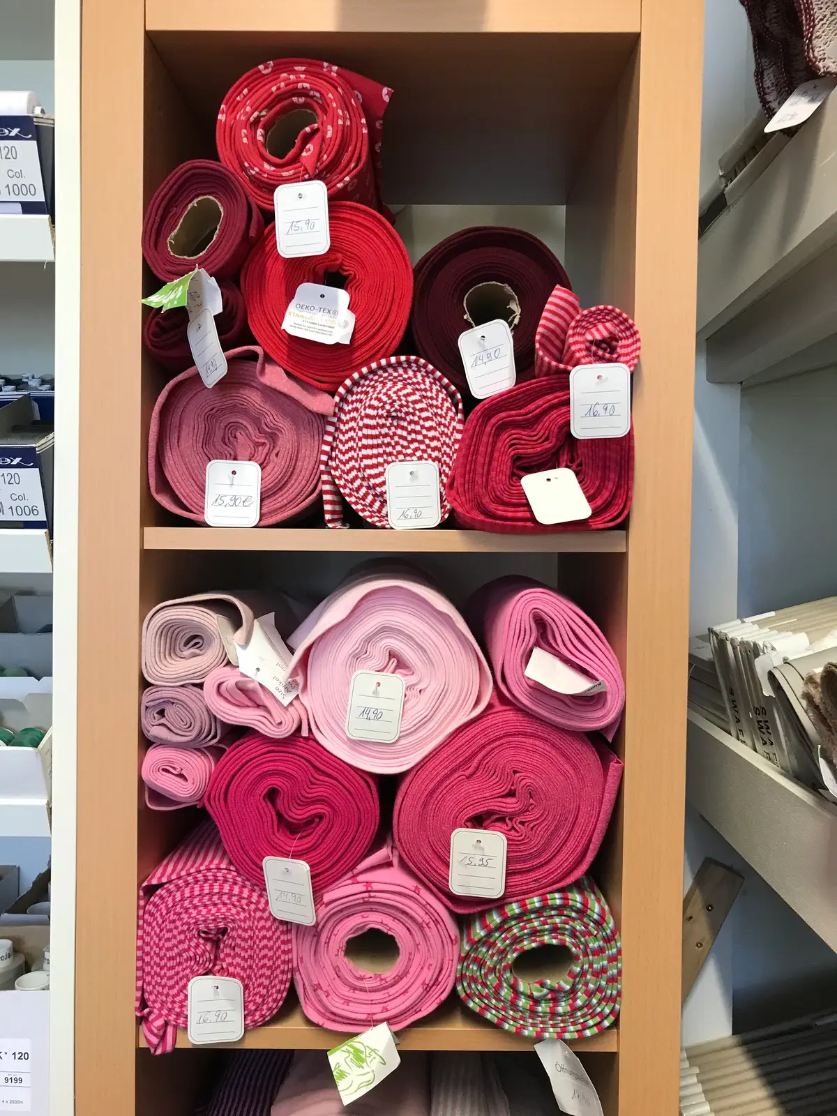 Stoffrollen in Rosa- und Rottönen im Regal