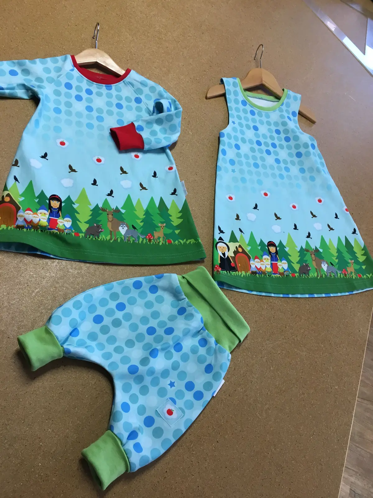 Hellblaue Kinderkleidchen mit Waldmotiv und eine Hose mit grünen Bündchen
