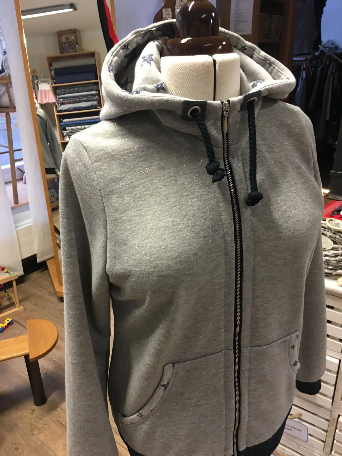 Graue Sweatjacke mit Kapuze auf der Schneiderbüste